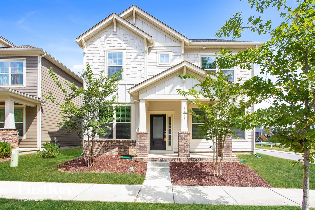 a white house with trees and a sidewalk in front of it