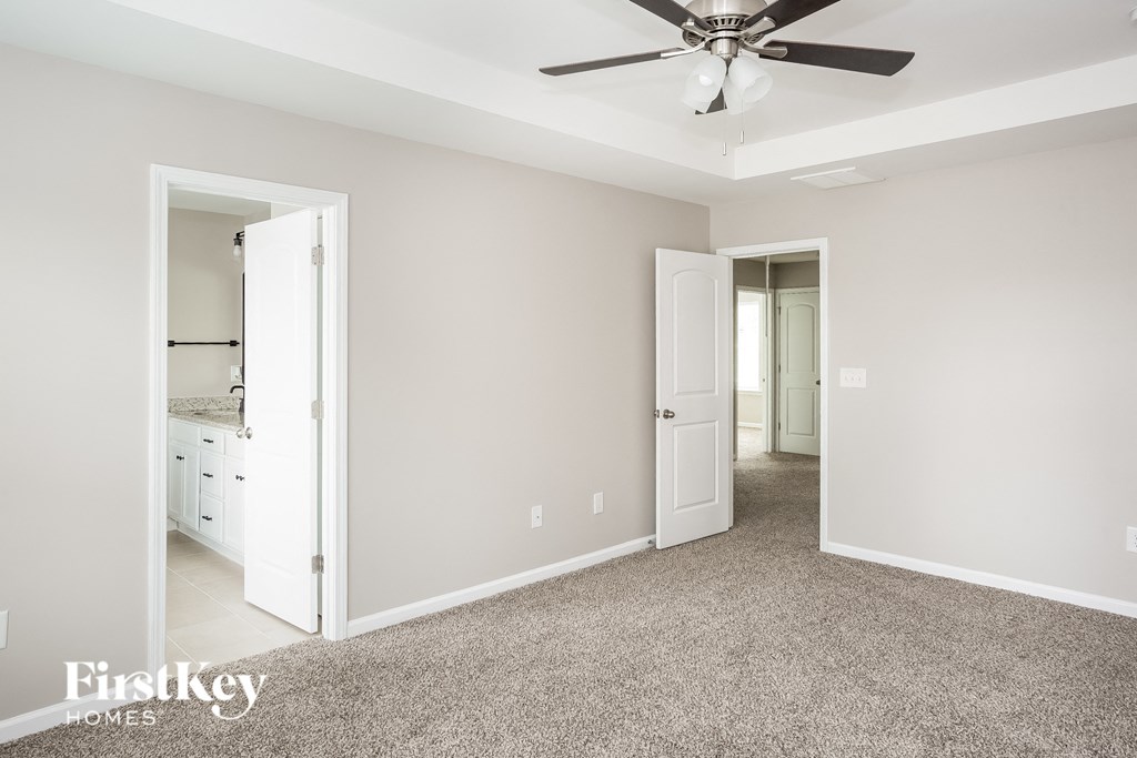 a bedroom with a ceiling fan and a door to a bathroom