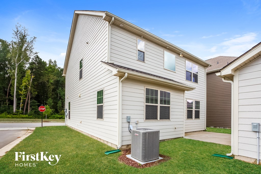 a side view of a white house with a trash can in the yard