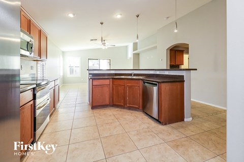 A kitchen with a tile floor and a counter with a trash can.