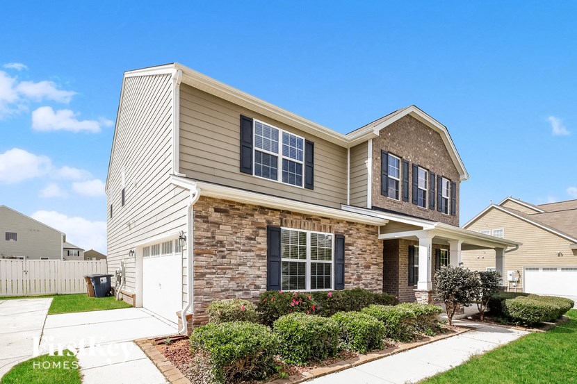 a beige house with a white fence and a lawn