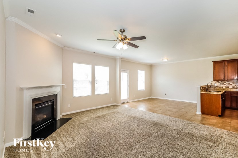 an empty living room with a fireplace and a ceiling fan