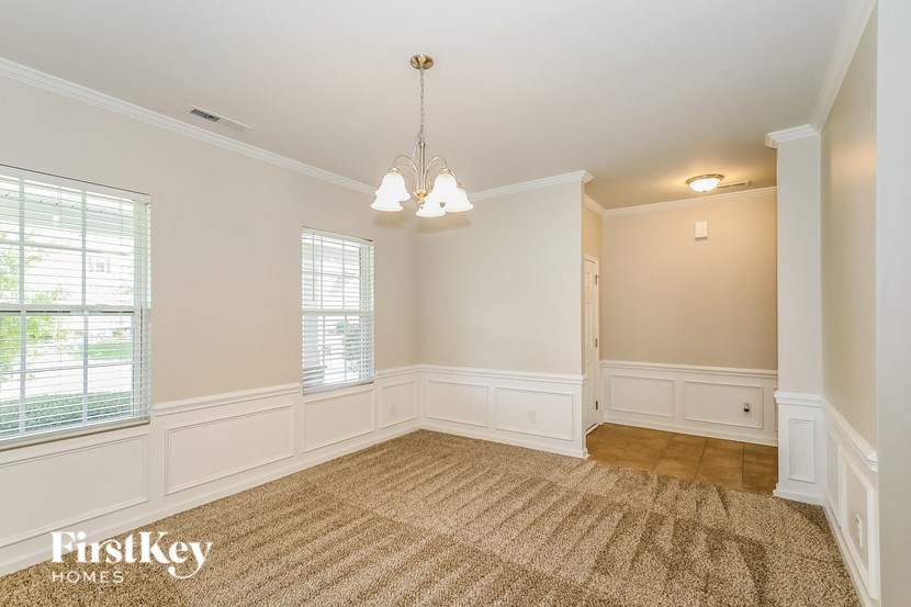 a dining room with white walls and a rug and a chandelier