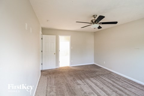 a living room with a ceiling fan and a carpet