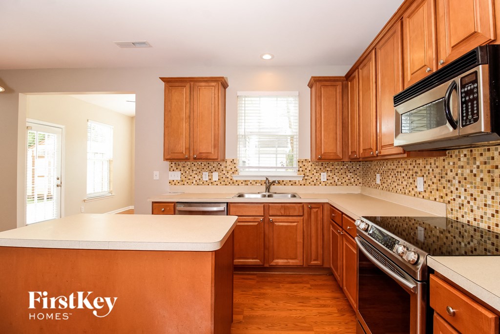A kitchen with wooden cabinets and a FirstKey Homes logo.