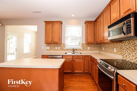 A kitchen with wooden cabinets and a FirstKey Homes logo.