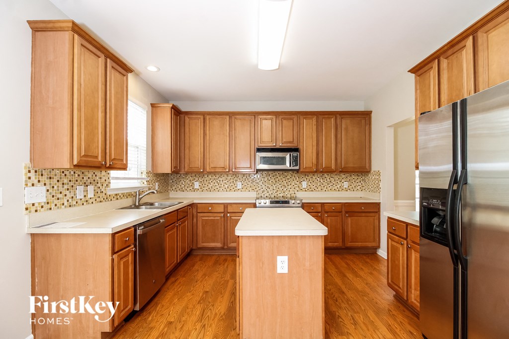 A kitchen with wooden cabinets and a black refrigerator.