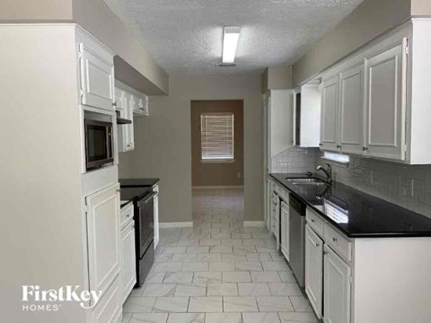 A kitchen with white cabinets and black countertops.