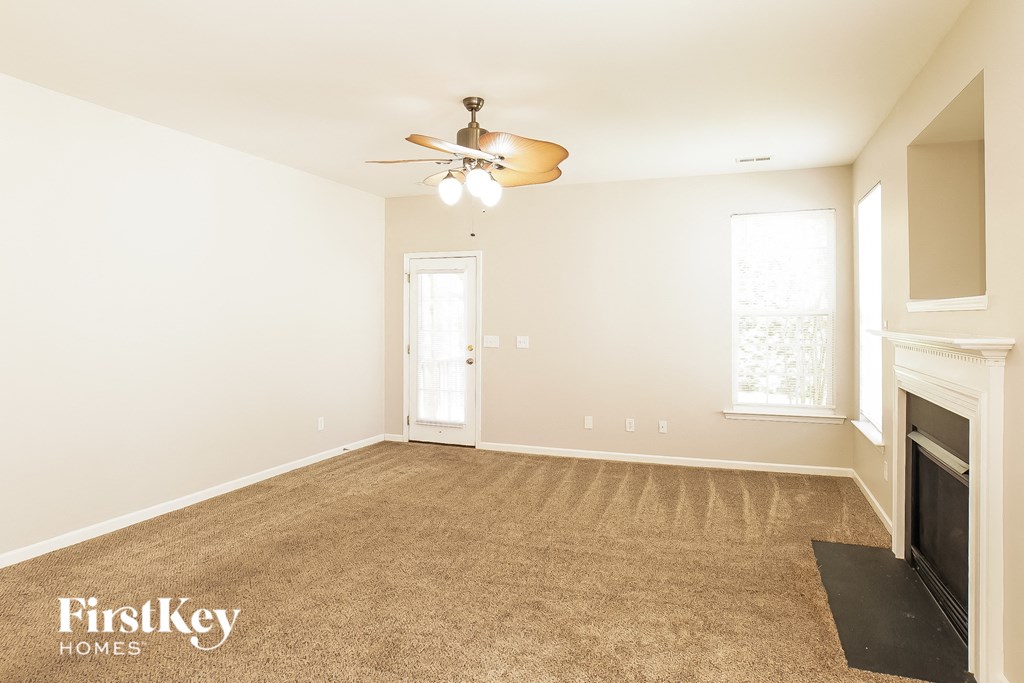 a empty living room with a fireplace and a ceiling fan