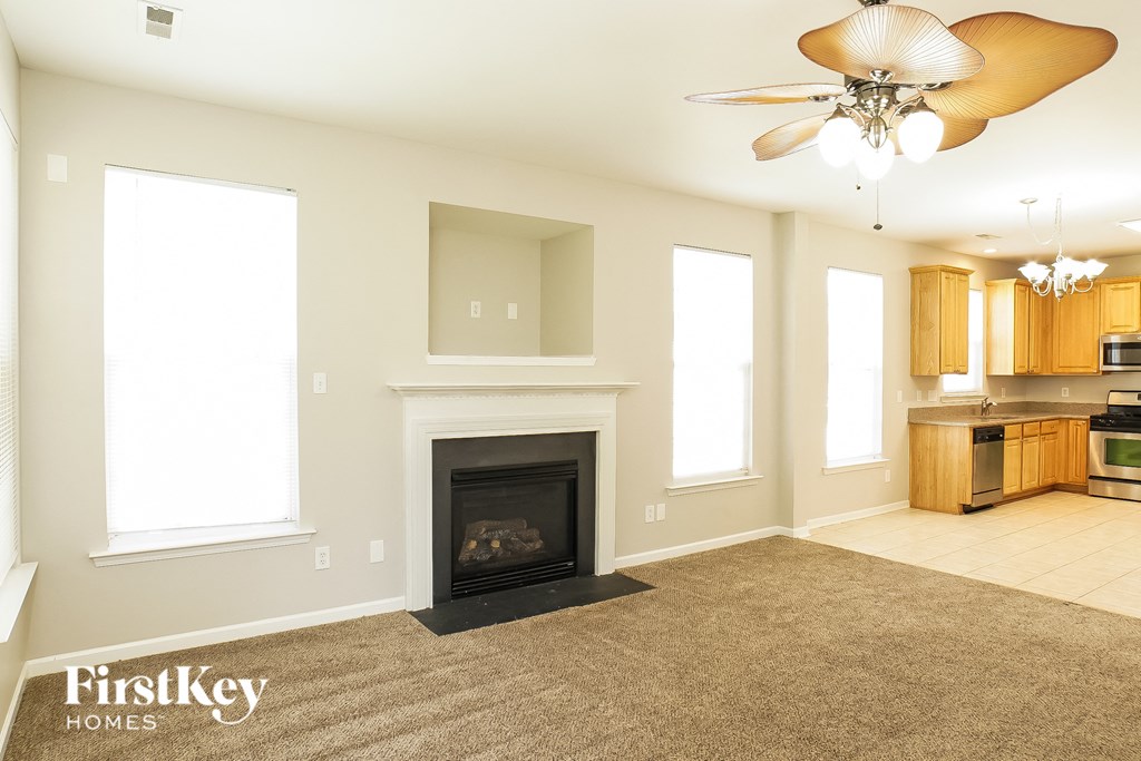 an empty living room with a fireplace and a kitchen