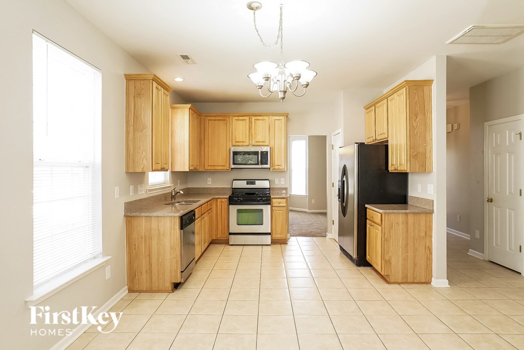a kitchen with wooden cabinets and appliances and tiled flooring