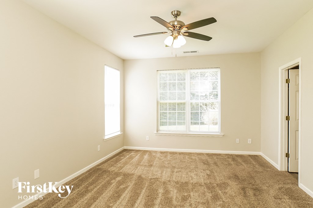 a spacious living room with carpet and a ceiling fan