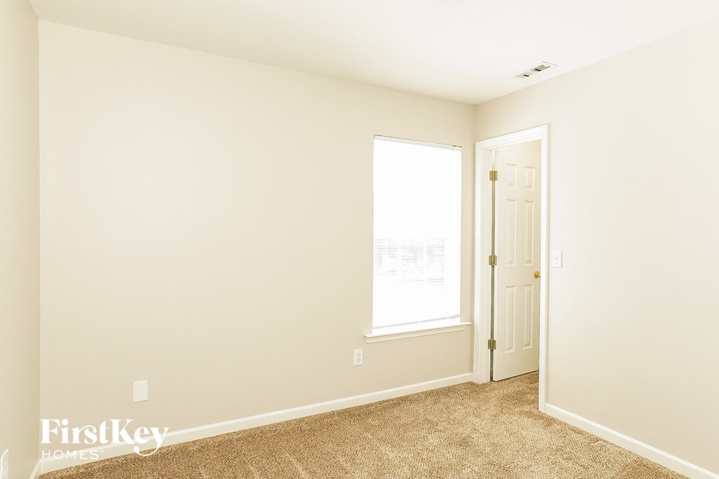 a bedroom with white walls and a door and a window