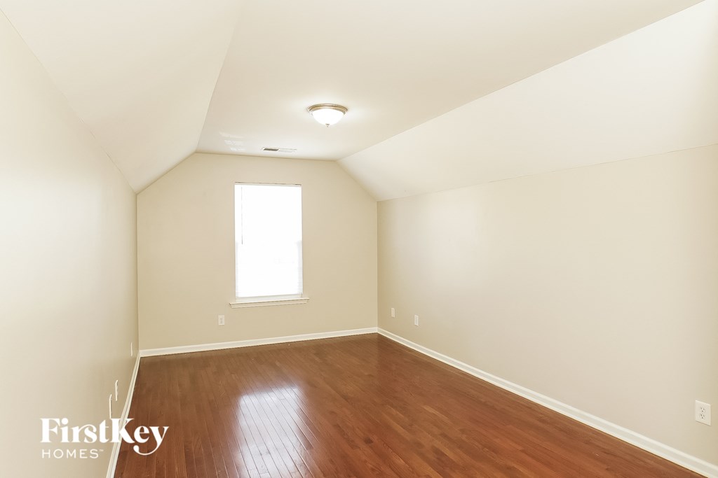 a bedroom with wood floors and white walls and a window