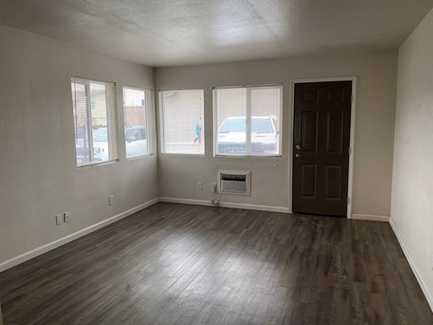 an empty living room with wood floors and a door