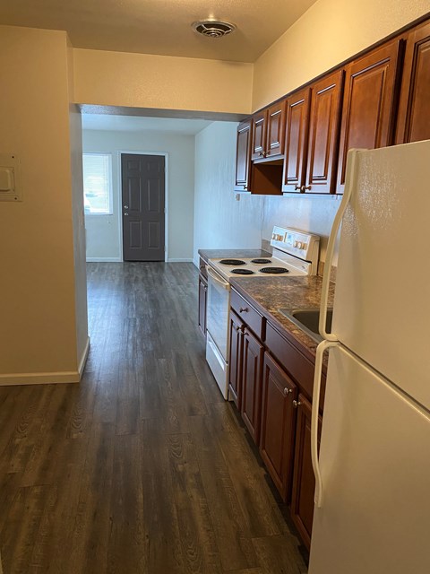 A kitchen with wooden cabinets and a white fridge.
