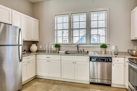A kitchen with white cabinets and a stainless steel refrigerator.