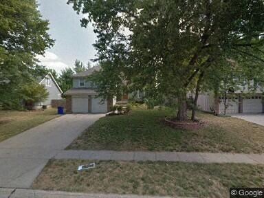 a street with a house and trees and a sidewalk
