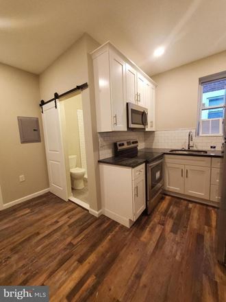 a kitchen with white cabinets and a sink and a toilet