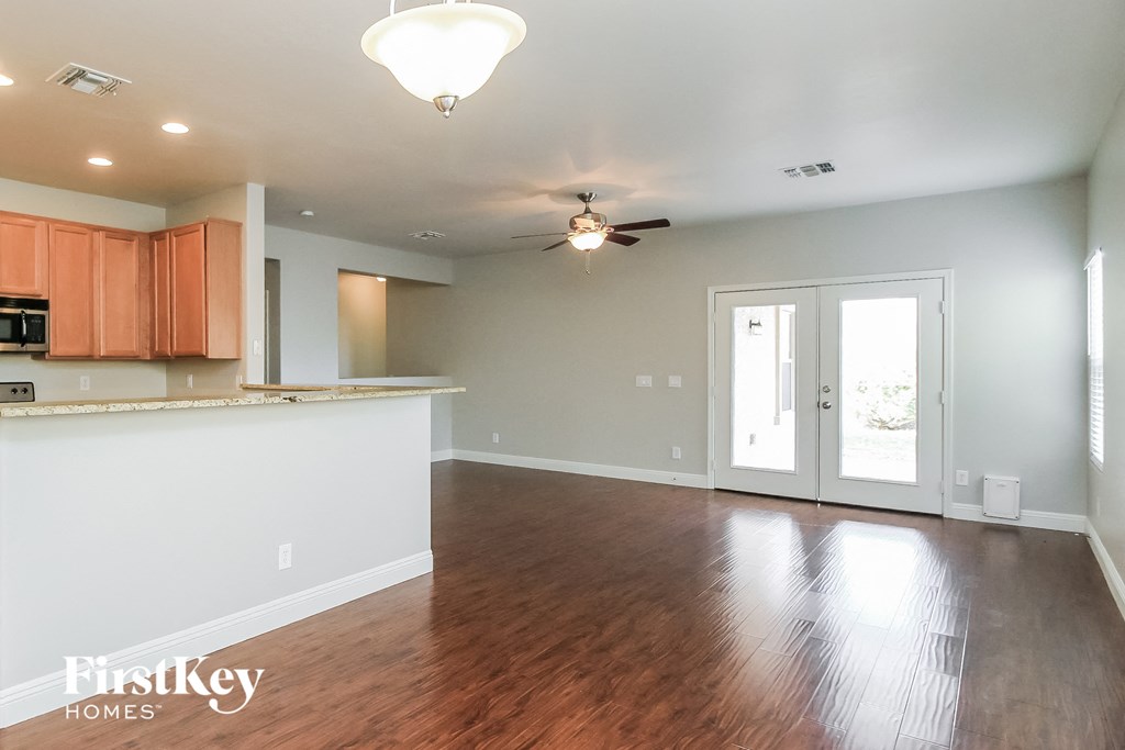 A spacious kitchen with wooden floors and a ceiling fan.