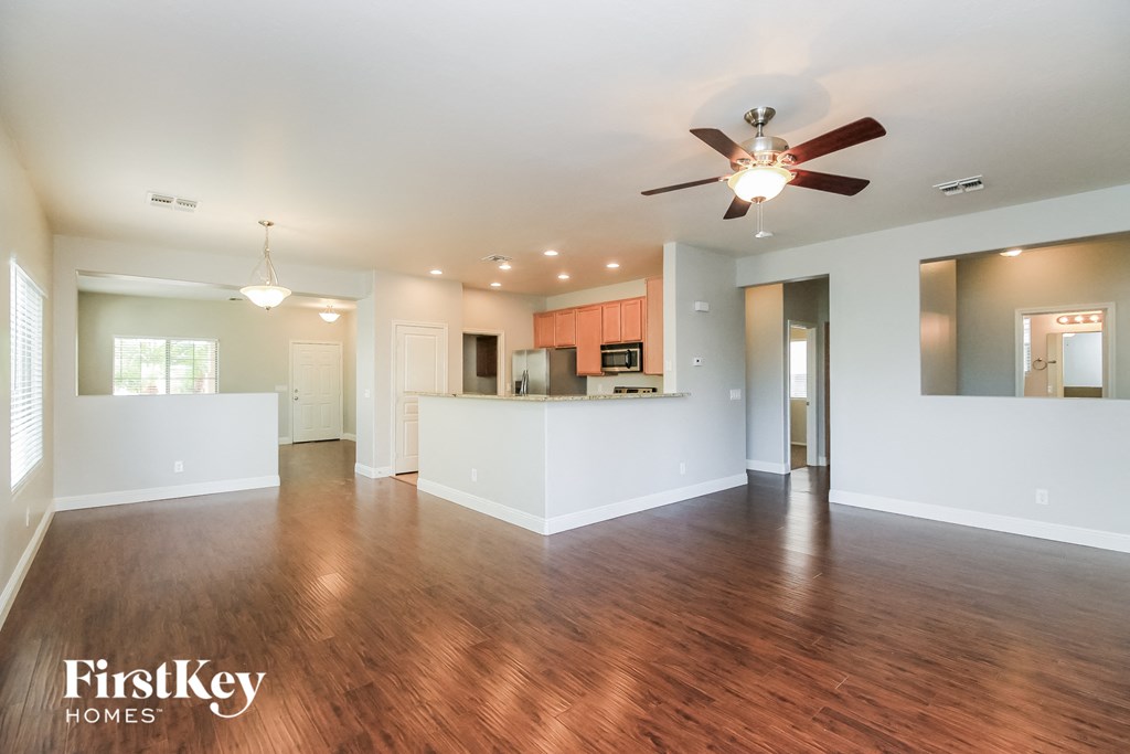A spacious room with wooden floors and a ceiling fan.