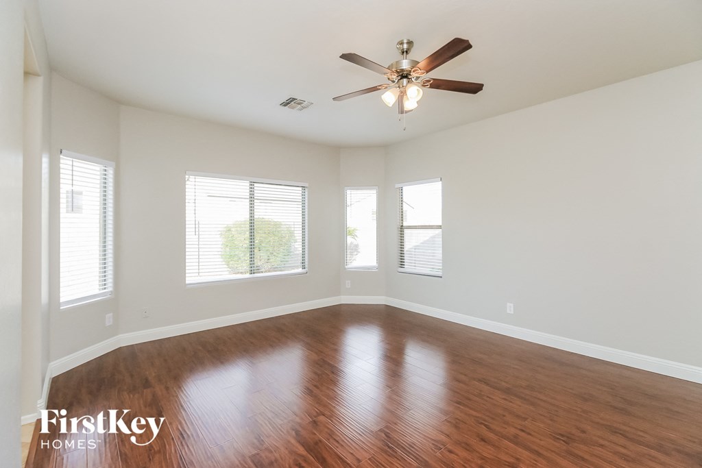 A room with a ceiling fan and wooden flooring.