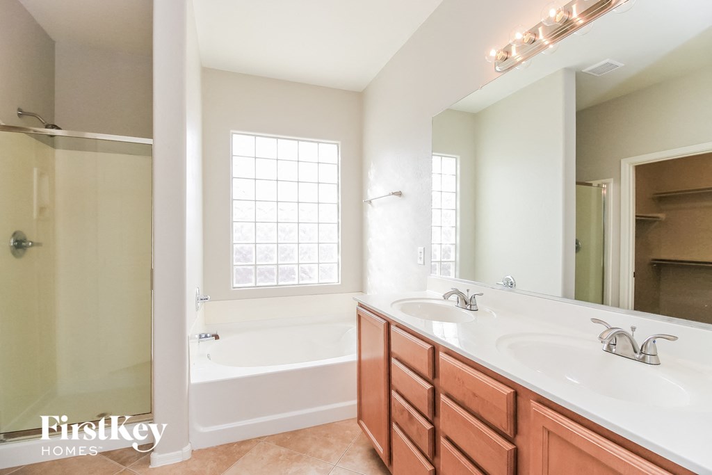 A bathroom with a tub, sink, and mirror.