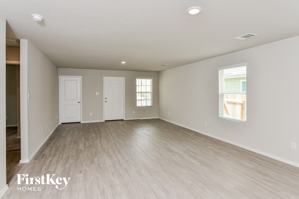 a spacious living room with white walls and wood flooring