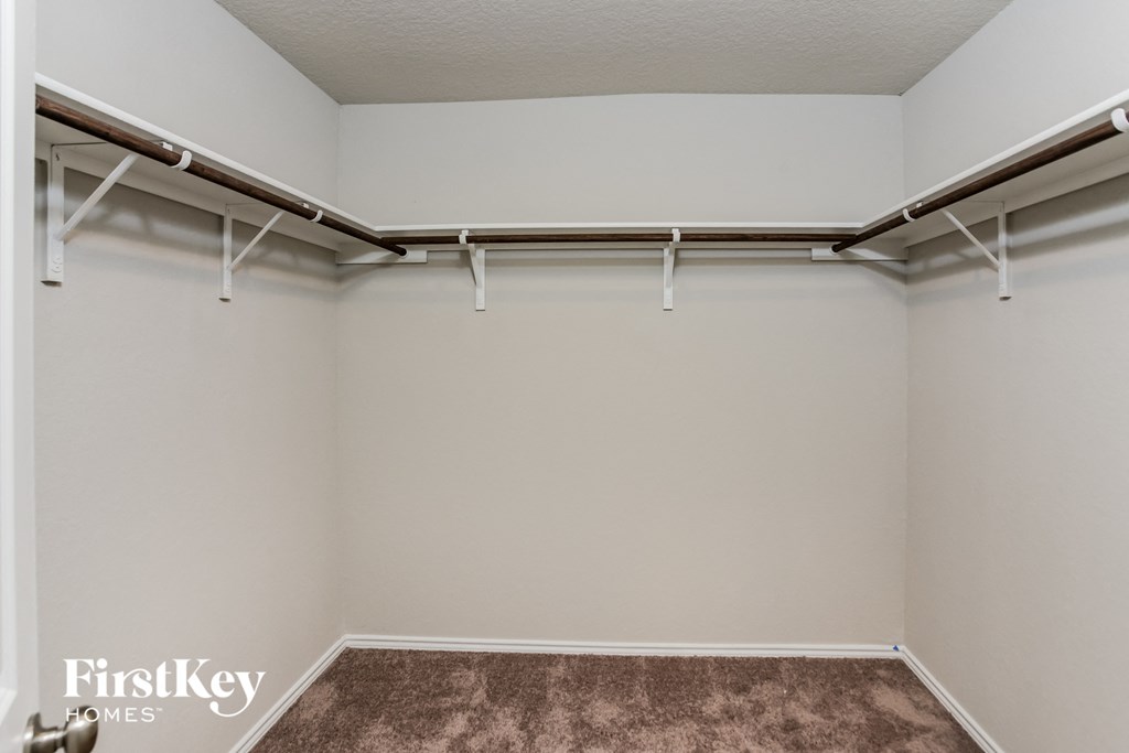 an empty closet with white walls and a brown carpet