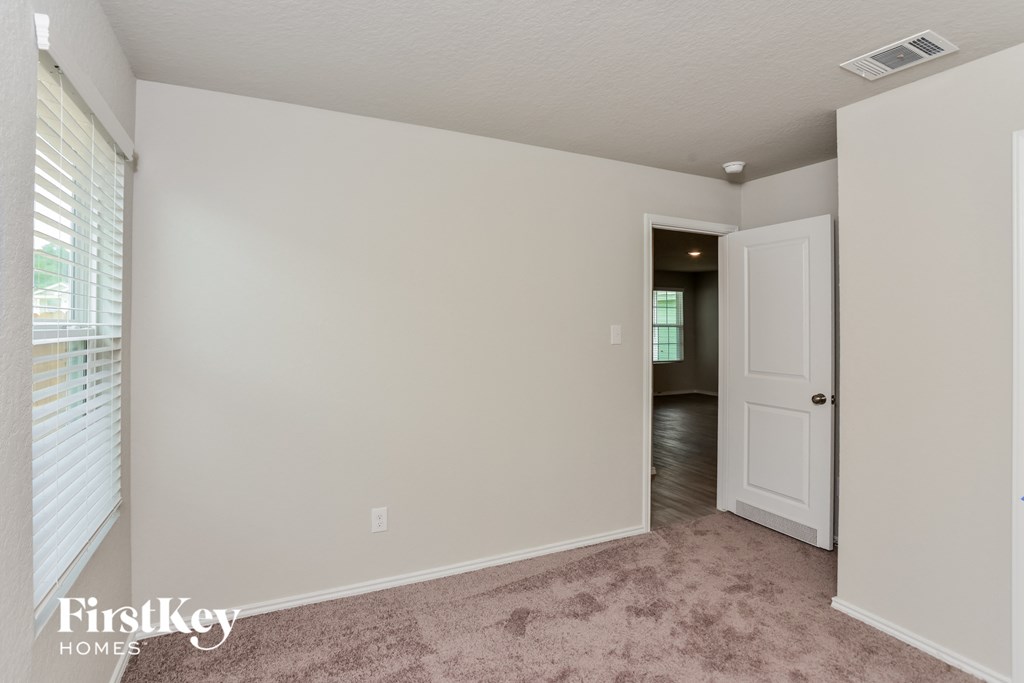 a bedroom with white walls and a door to a hallway