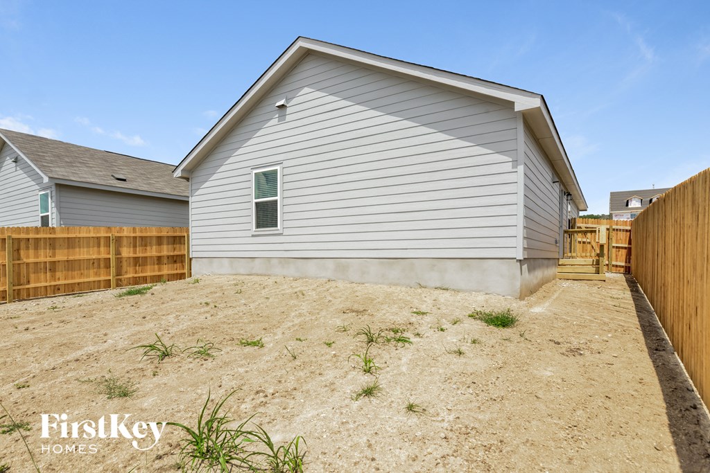a backyard with a wooden fence and a white house