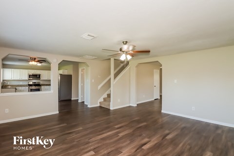 A spacious room with wooden floors and a staircase leading to another room.