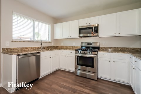 A kitchen with white cabinets and a granite countertop.