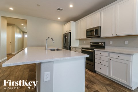 A kitchen with white cabinets and a white island with a sink.