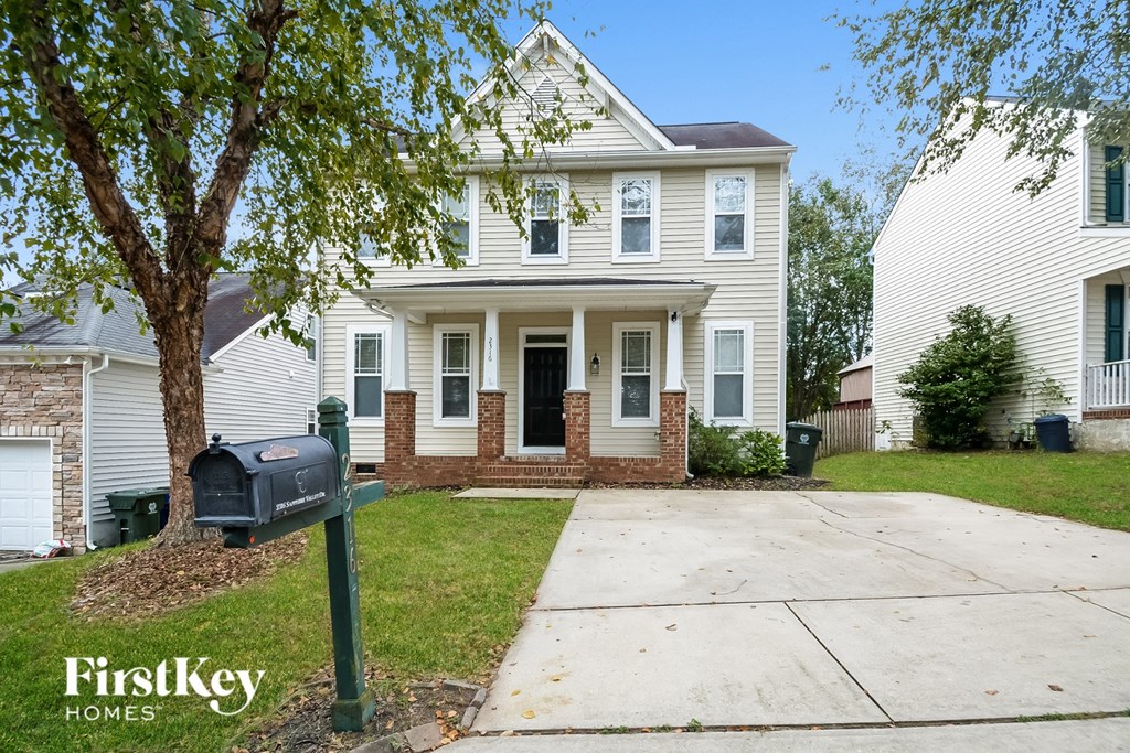 A two-story house with a white exterior and a black mailbox in front.