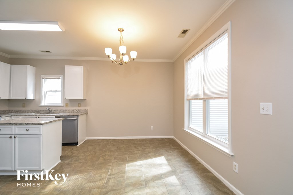 A well-lit kitchen and living room with a chandelier and a window.