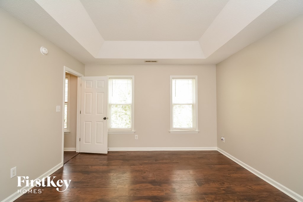 A room with wooden floors and two windows.