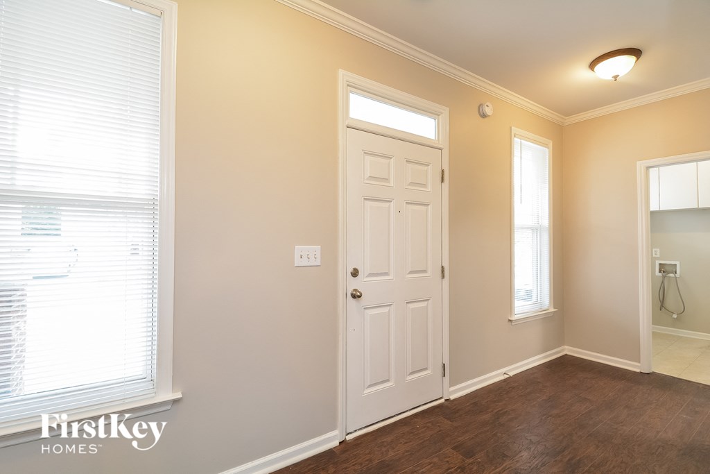 A room with a door, a window with blinds, and a light on the ceiling.