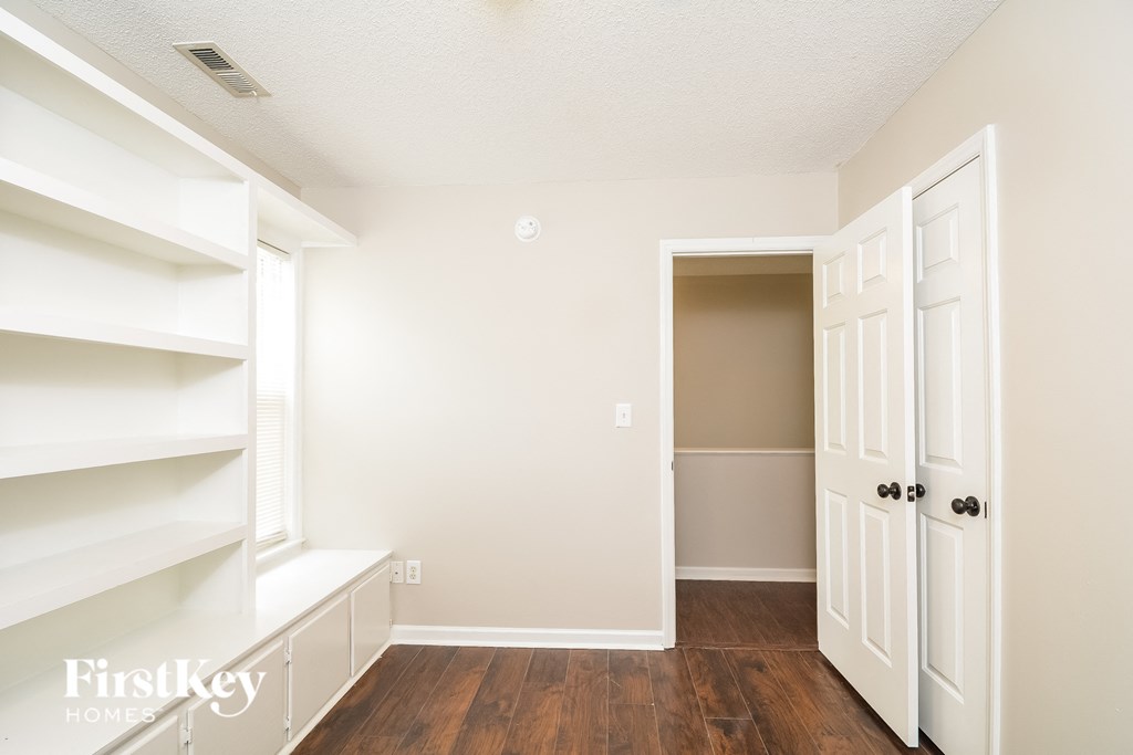 A room with a white door and a white shelf.