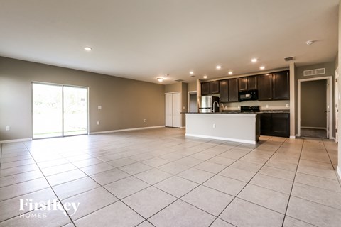an empty living room and kitchen with a large tiled floor
