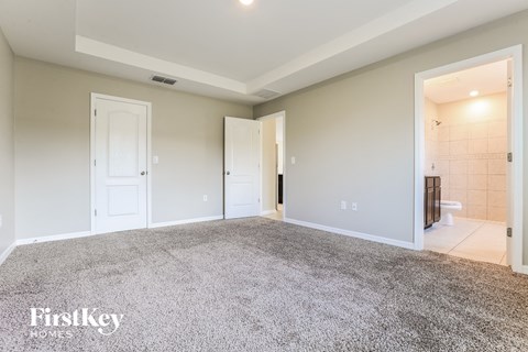 a master bedroom with a carpeted floor and a tiled bathroom
