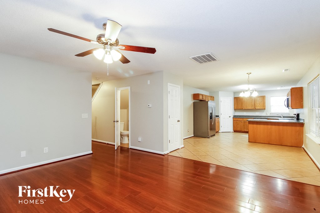 an empty living room and kitchen with wood floors and a ceiling fan