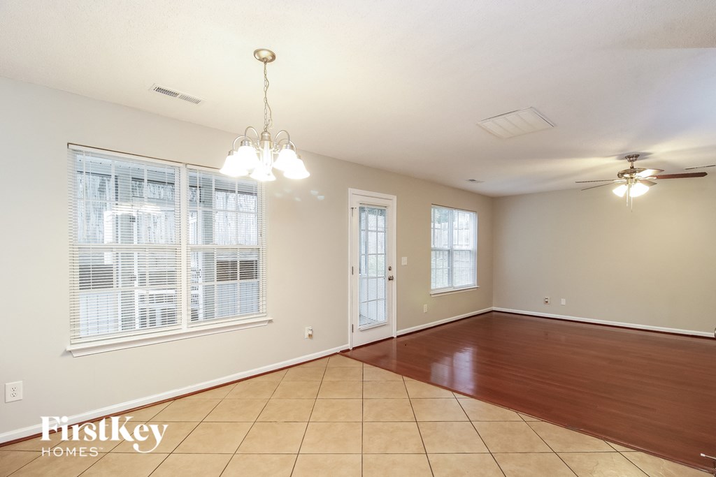 a spacious living room with a large window and wood flooring