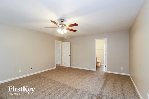 a spacious living room with carpet and a ceiling fan