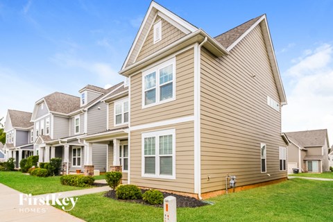 a row of houses with tan siding and green grass