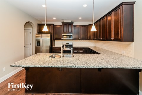 an updated kitchen with granite counter tops and dark wood cabinets