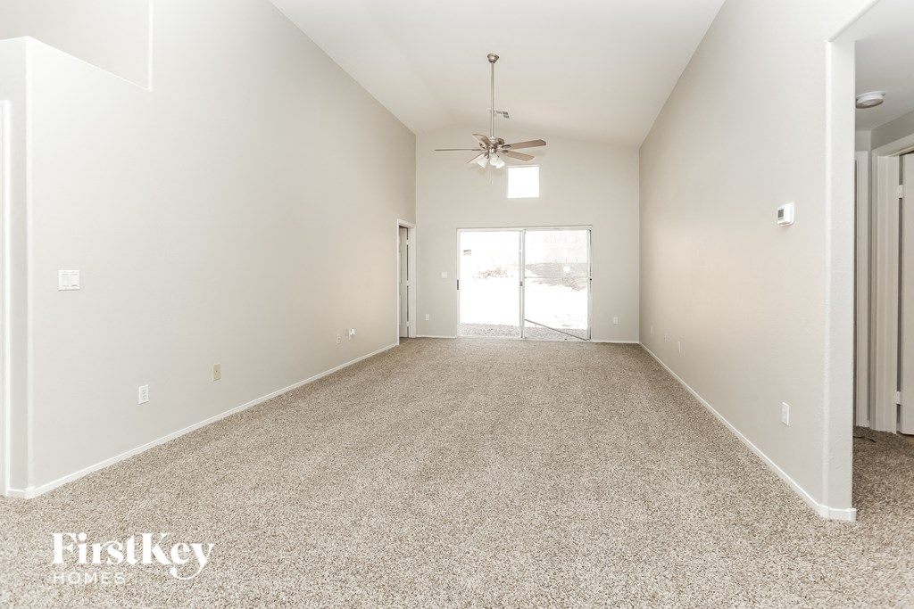 a spacious living room with carpet and a ceiling fan
