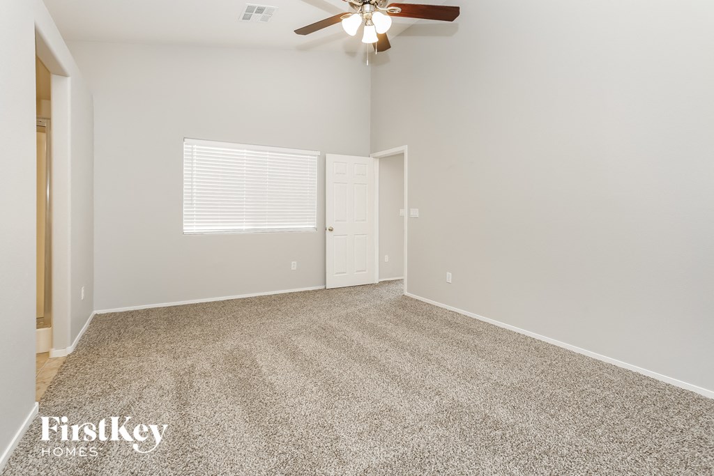 the spacious living room with ceiling fan and carpet