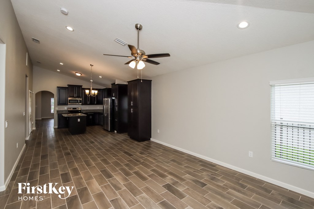 A spacious room with a fan and wooden flooring.