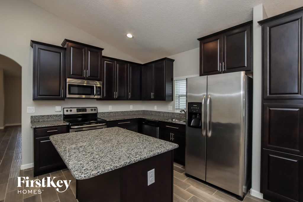 A kitchen with dark brown cabinets and a granite countertop.